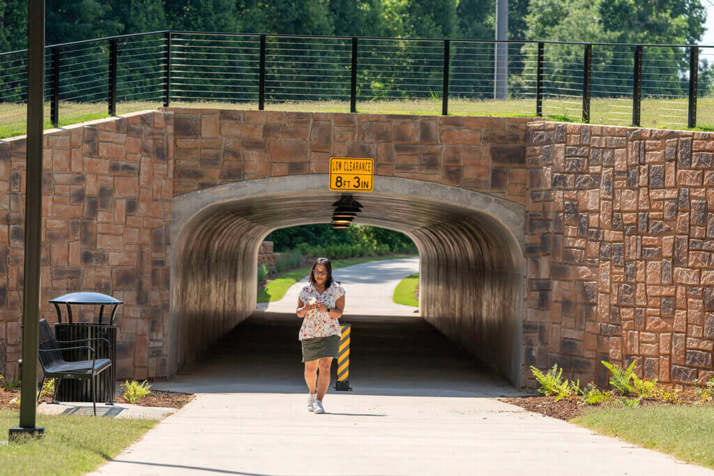 A woman walks through a tunnel on the Alpha Loop trail